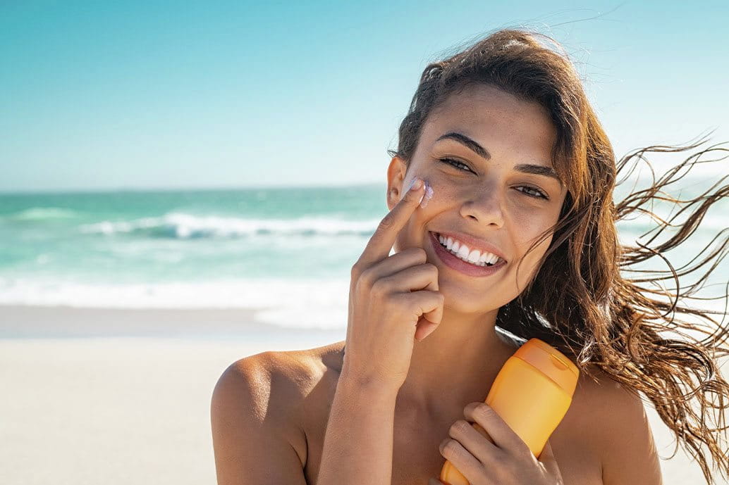 foto ragazza che applica crema solare viso