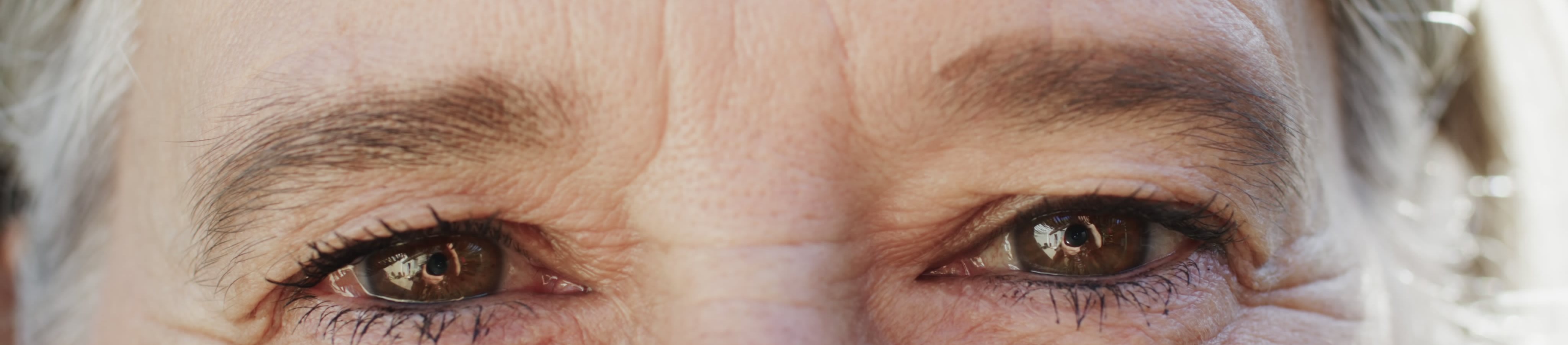 Close-up photograph of an older person’s eyes, showing visible fine lines and wrinkles around the eyes and forehead.