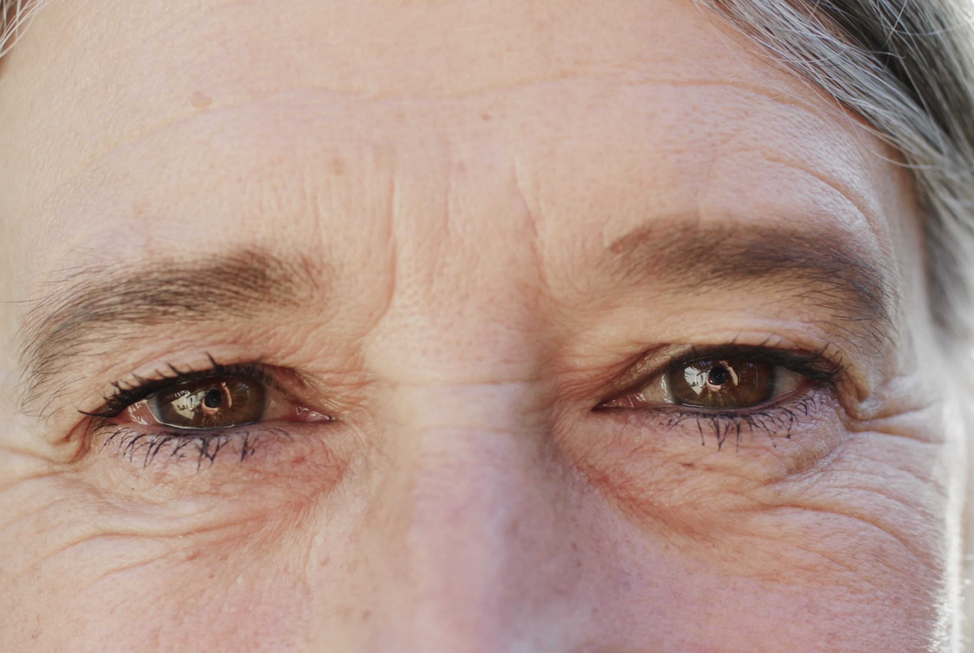 Close-up photograph of an older person’s eyes, showing visible fine lines and wrinkles around the eyes and forehead.