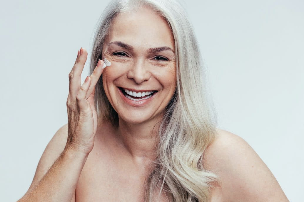 donna anziana che applica la crema