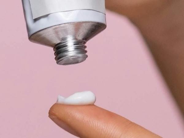 Eine Frau trägt sich ein Eucerin Pflegeprodukt auf die Fingerspitze auf.