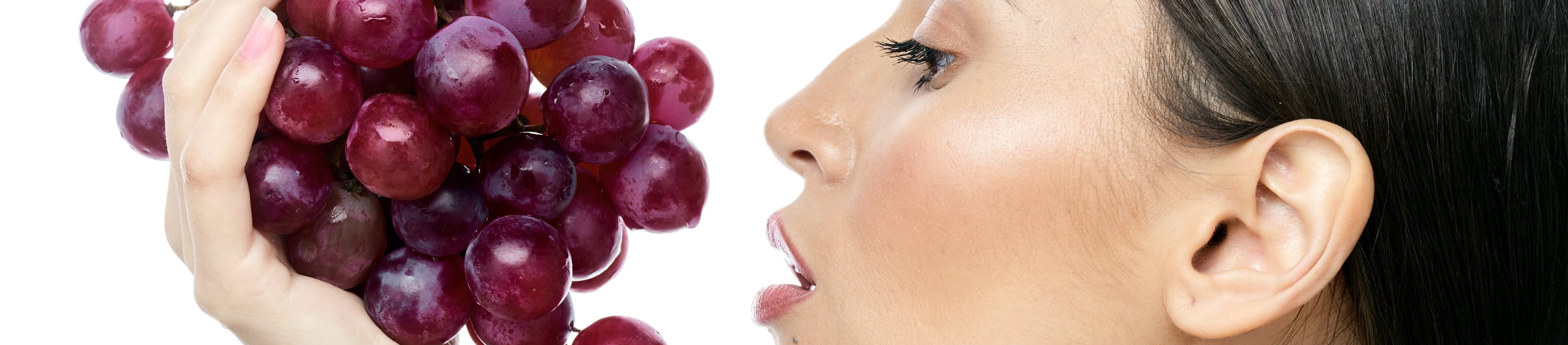 Profilansicht einer Frau, die eine Traubenrebe in der Hand hält.