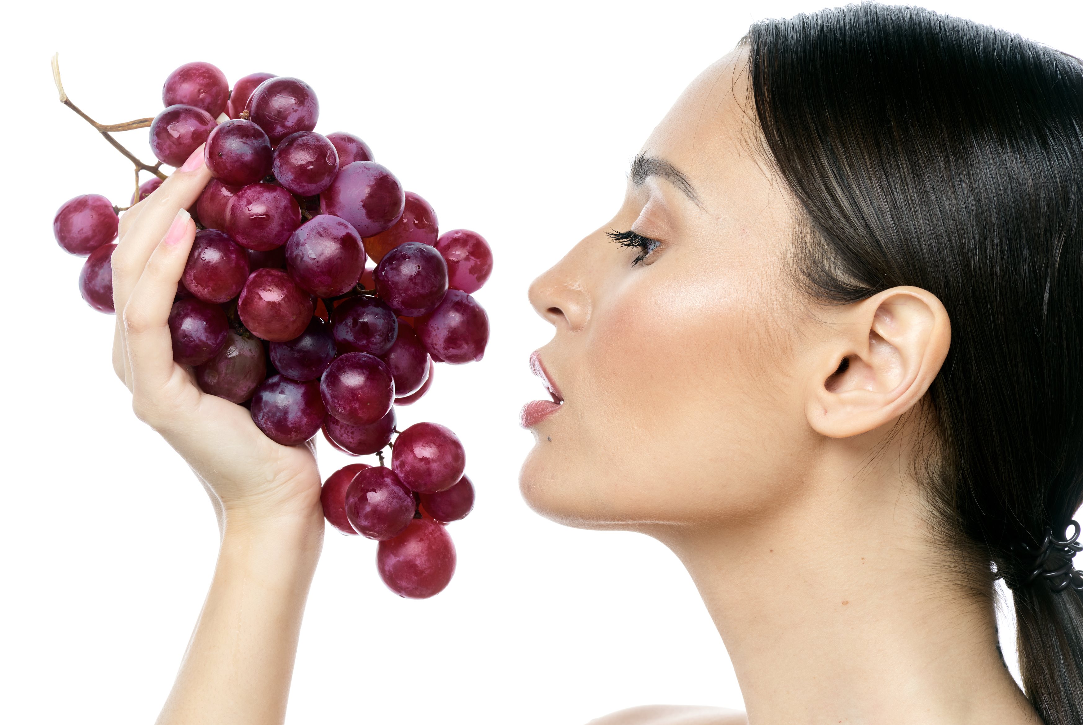 Profilansicht einer Frau, die eine Traubenrebe in der Hand hält.