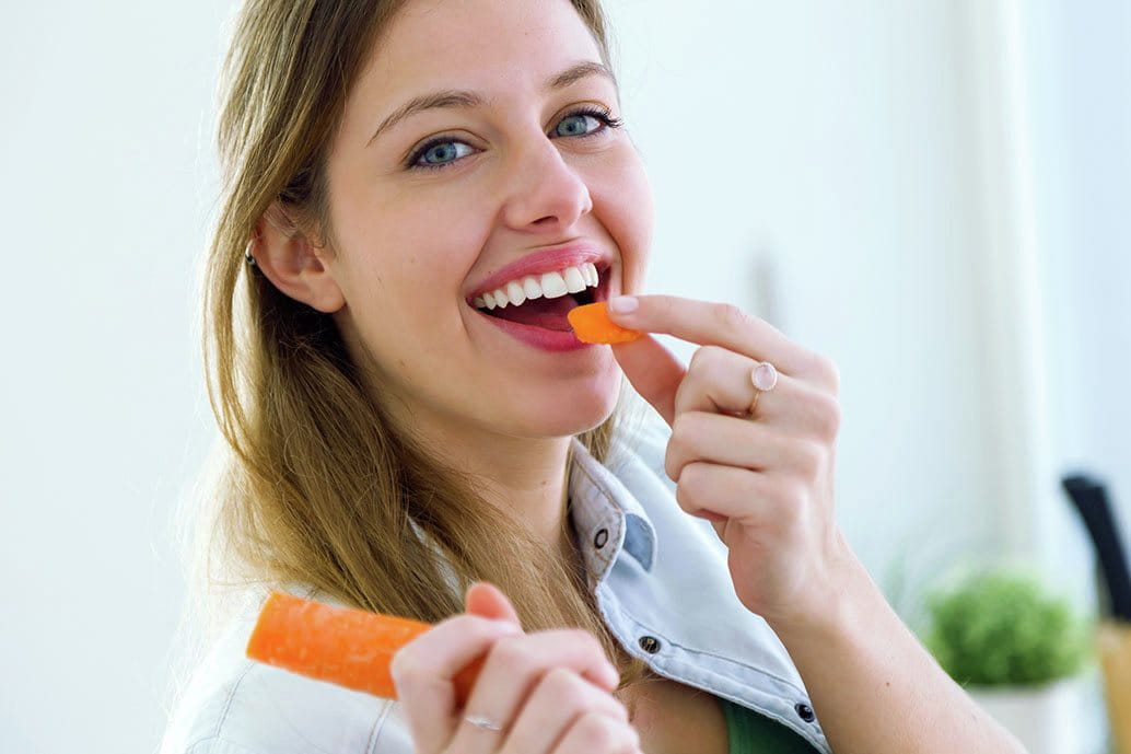 Donna che mangia carote che prolungano l'abbronzatura dall'interno