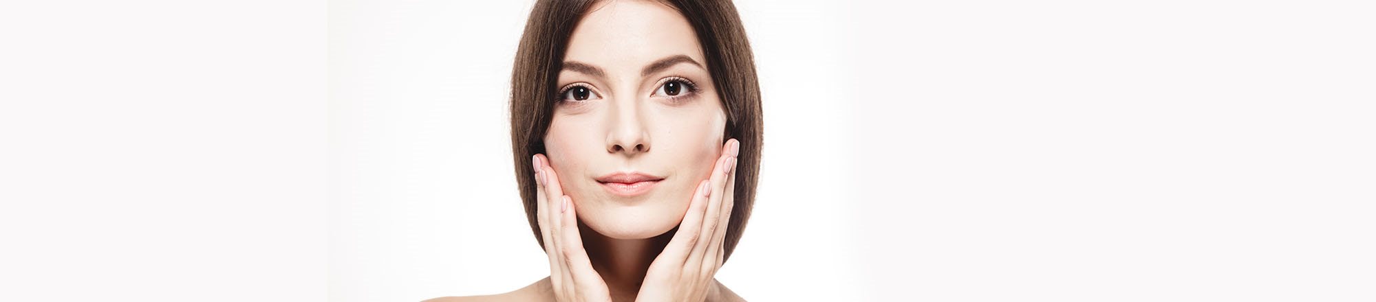 Ritratto di donna con pelle curata, tocco leggero della mano sul viso come segno di cura.