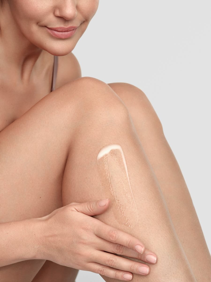 A woman applying lotion to her legs