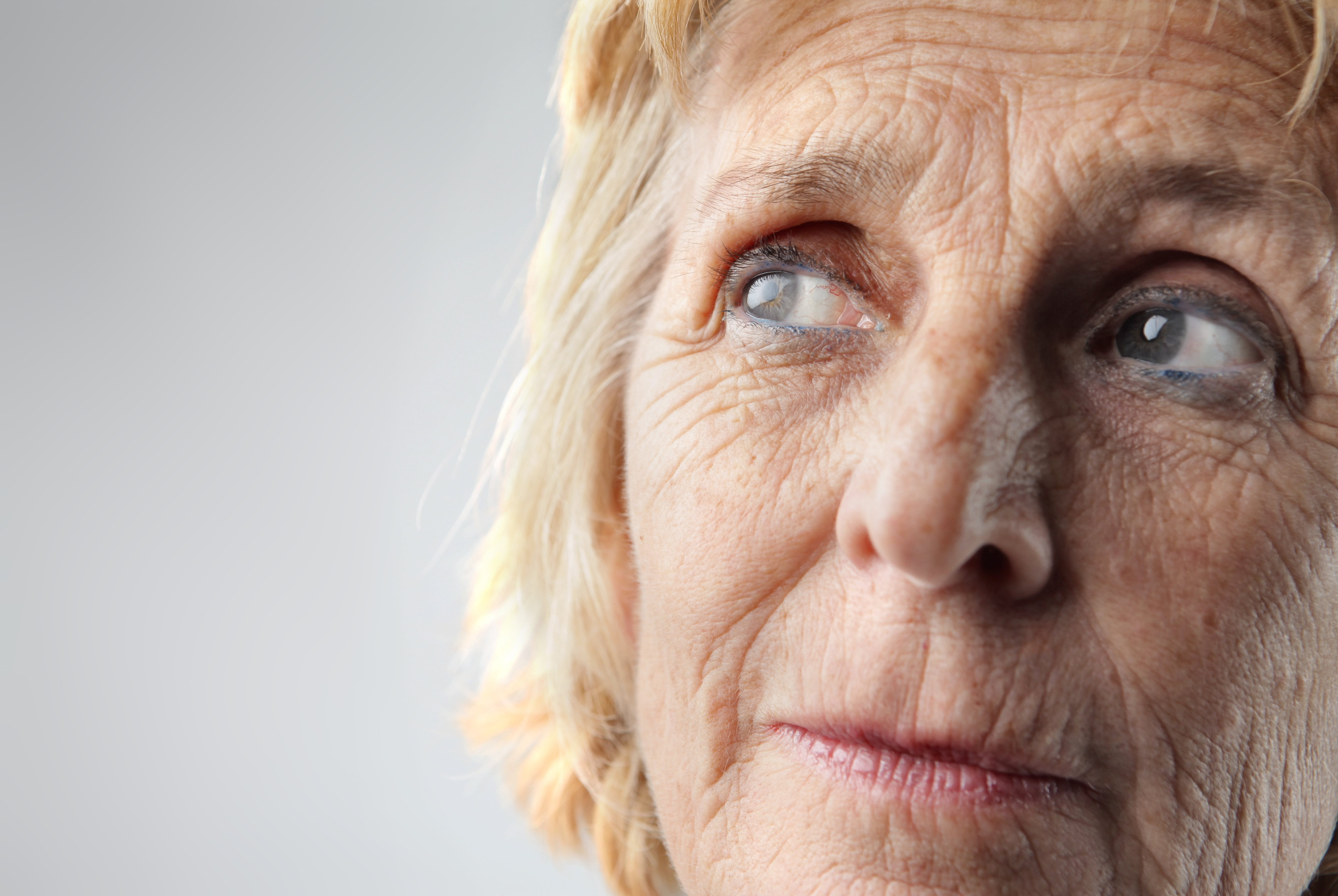 Gesicht einer älteren Frau mit braunen Augen und tiefen Falten um die Augen und auf der Stirn