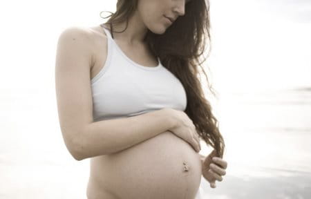 Gravid kvinna med sin hand på magen
