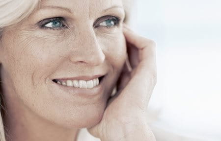 Middle-aged woman is touching her face with her hand.