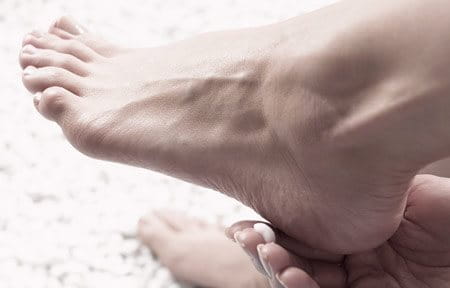 Woman applying lotion on heel.
