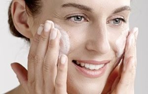 Una mujer se aplica gel limpiador en la cara.