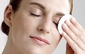 Una mujer elimina el maquillaje de sus ojos con una gasa de algodón