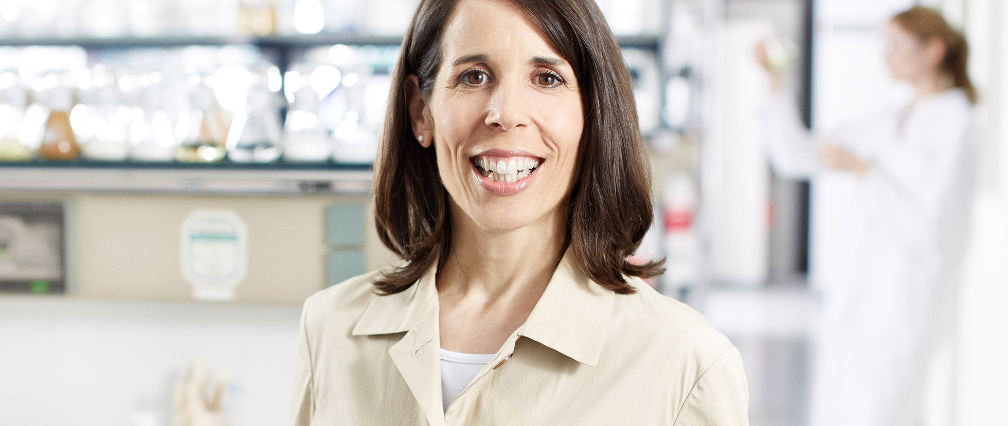 Smiling woman in a lab coat standing in a laboratory.