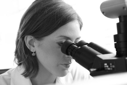 žena gleda kroz mikroskop