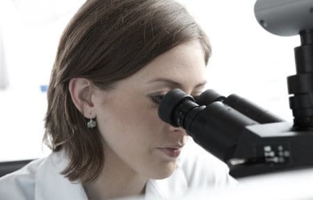 znanstvenica gleda kroz mikroskop