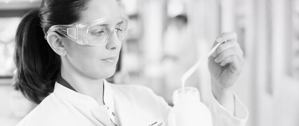 Female scientist with safety goggles testing a formula