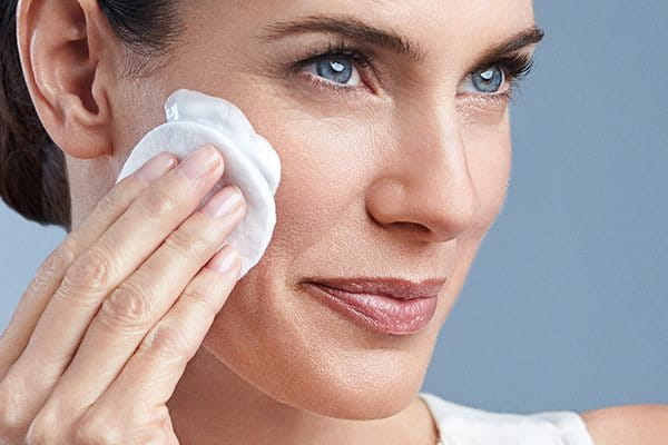 Kvinna som rengör sitt ansikte med Eucerin DermatoClean Micellar Foam