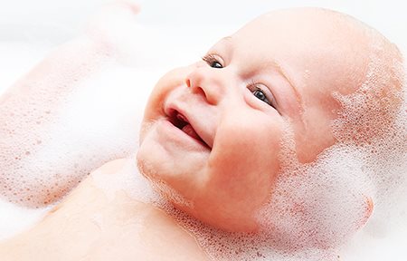 A baby smiling in a bath