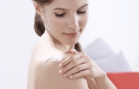 Mujer aplicándose loción corporal para piel sensible