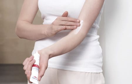 Woman applying Eucerin AtopiControl Care Cream on the crook of her arm.