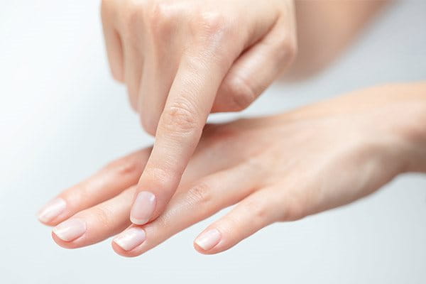 Woman pointing towards the finger nail on her ring finger