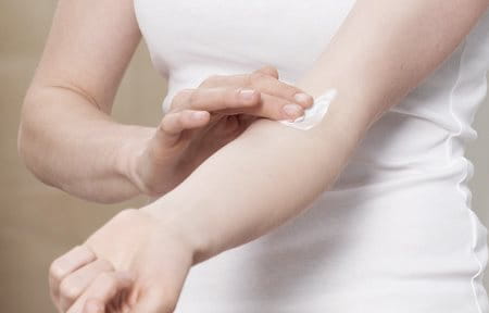 Woman applying cream on the crook of her arm