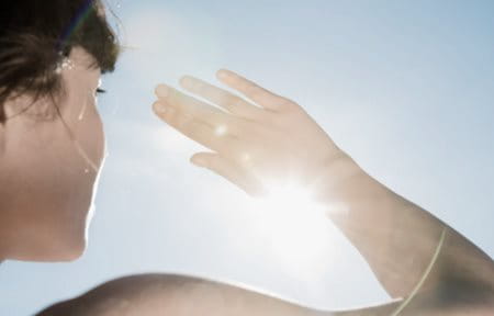 Woman protecting her face from sun with one hand