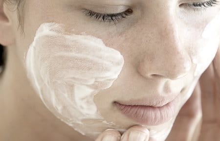 Woman applying skin care cream to her face.