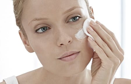Woman applying moisturiser to her face.
