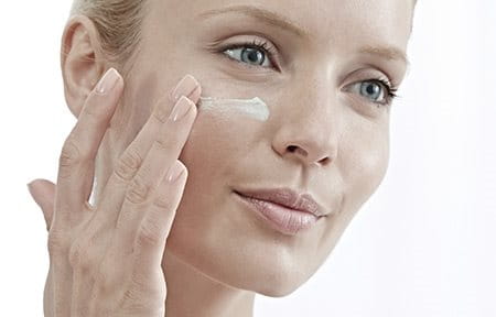 Woman applying Eucerin AntiREDNESS Concealing Day Care SPF 25 under her eye.