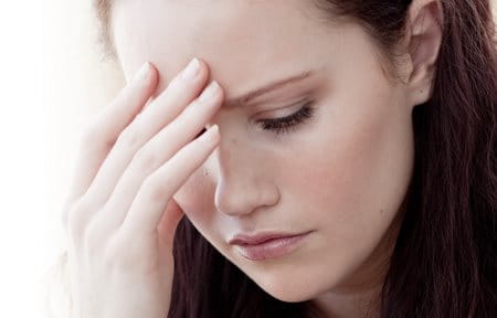 Stressed woman with hand to forehead.