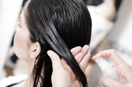 A woman having oil sprayed on her hair