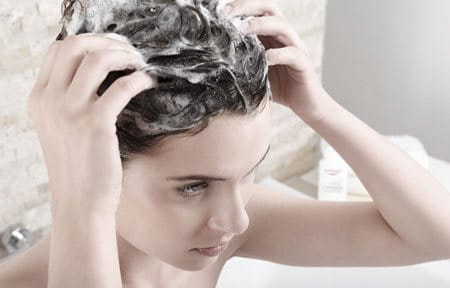 Frau massiert Shampoo sanft in ihre Kopfhaut ein.