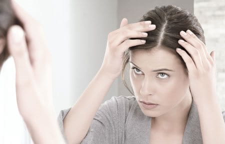 Woman looking at her scalp in the mirror