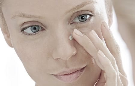 Woman applying concealing cream on her nose.