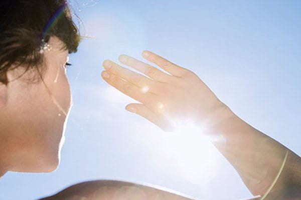 Woman protecting her face from the sun with her hand