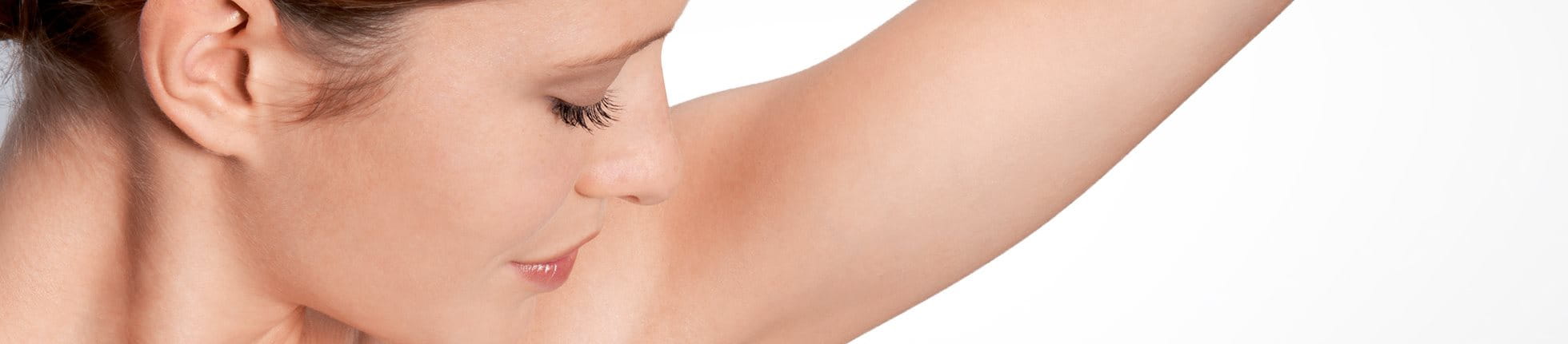 Woman examining underarm for deodorant intolerance.