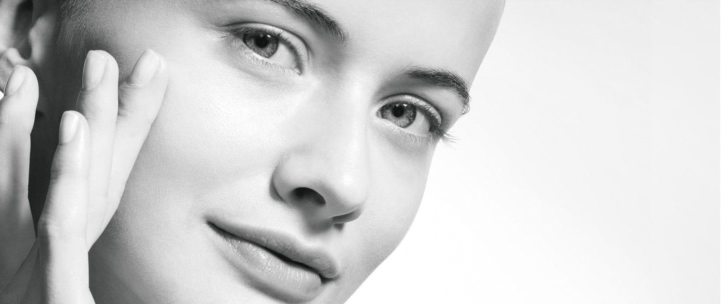 Close-up of a woman with clear skin touching her face.