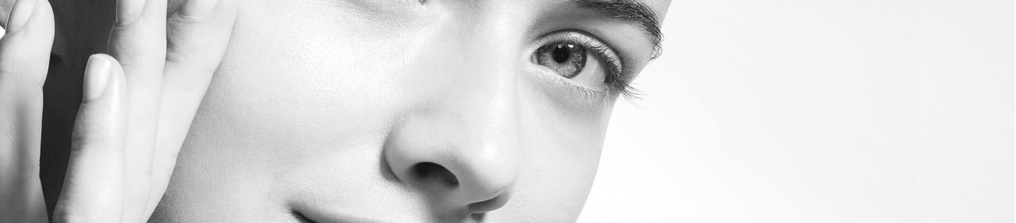 Close-up of a woman with clear skin touching her face.