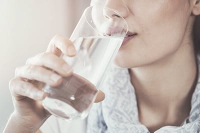 Frau trinkt aus Wasserglas