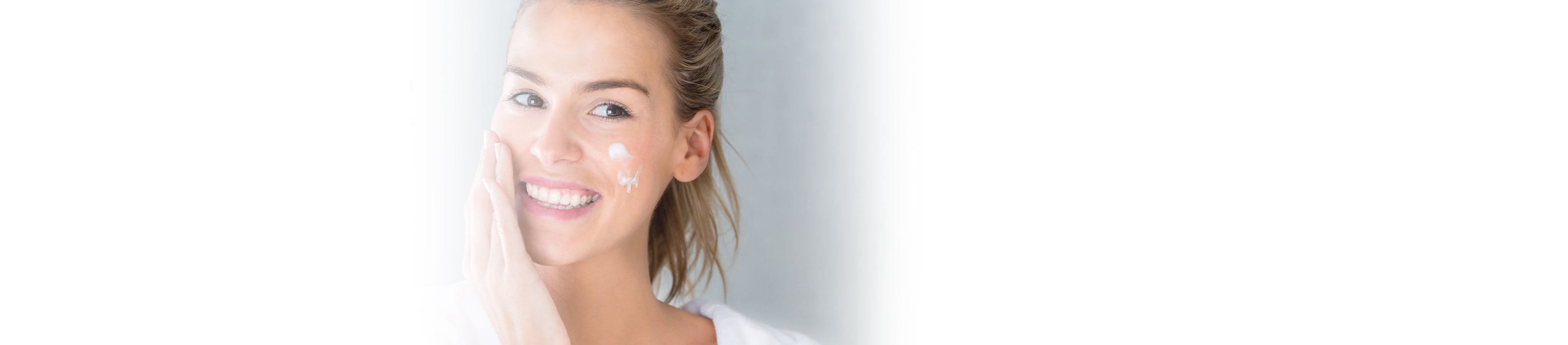 Frau cremt Gesicht ein