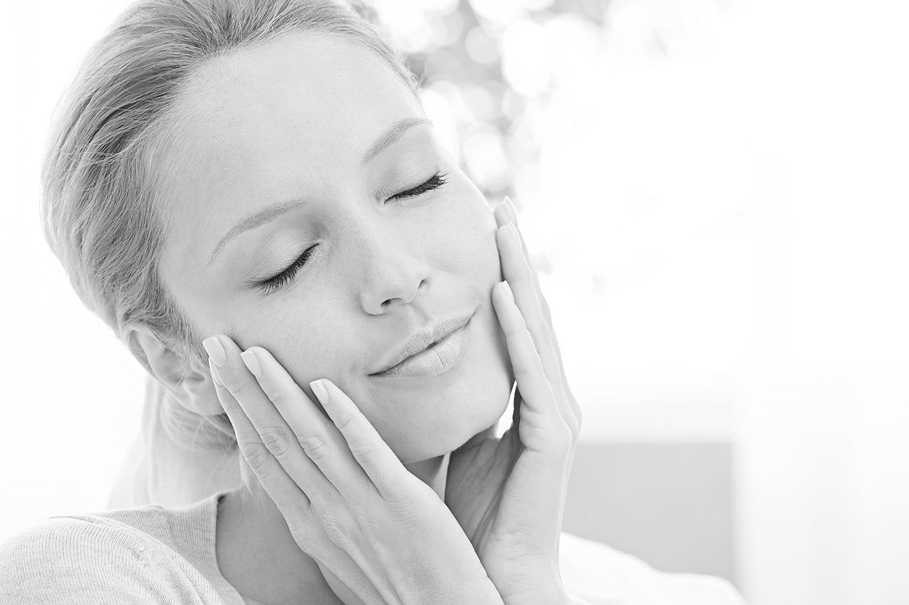 Frau greift sich mit Händen sanft ins Gesicht 