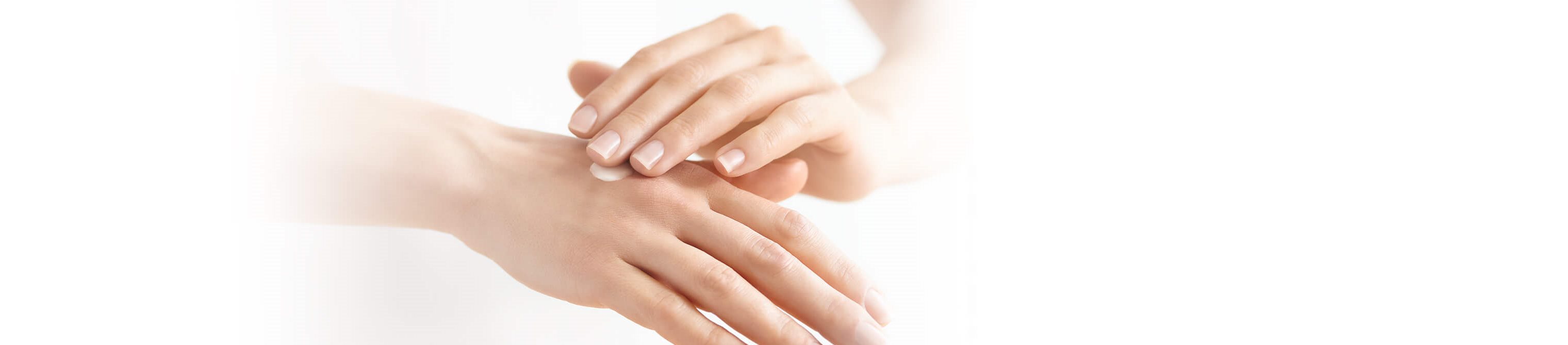 Frau cremet Hand ein