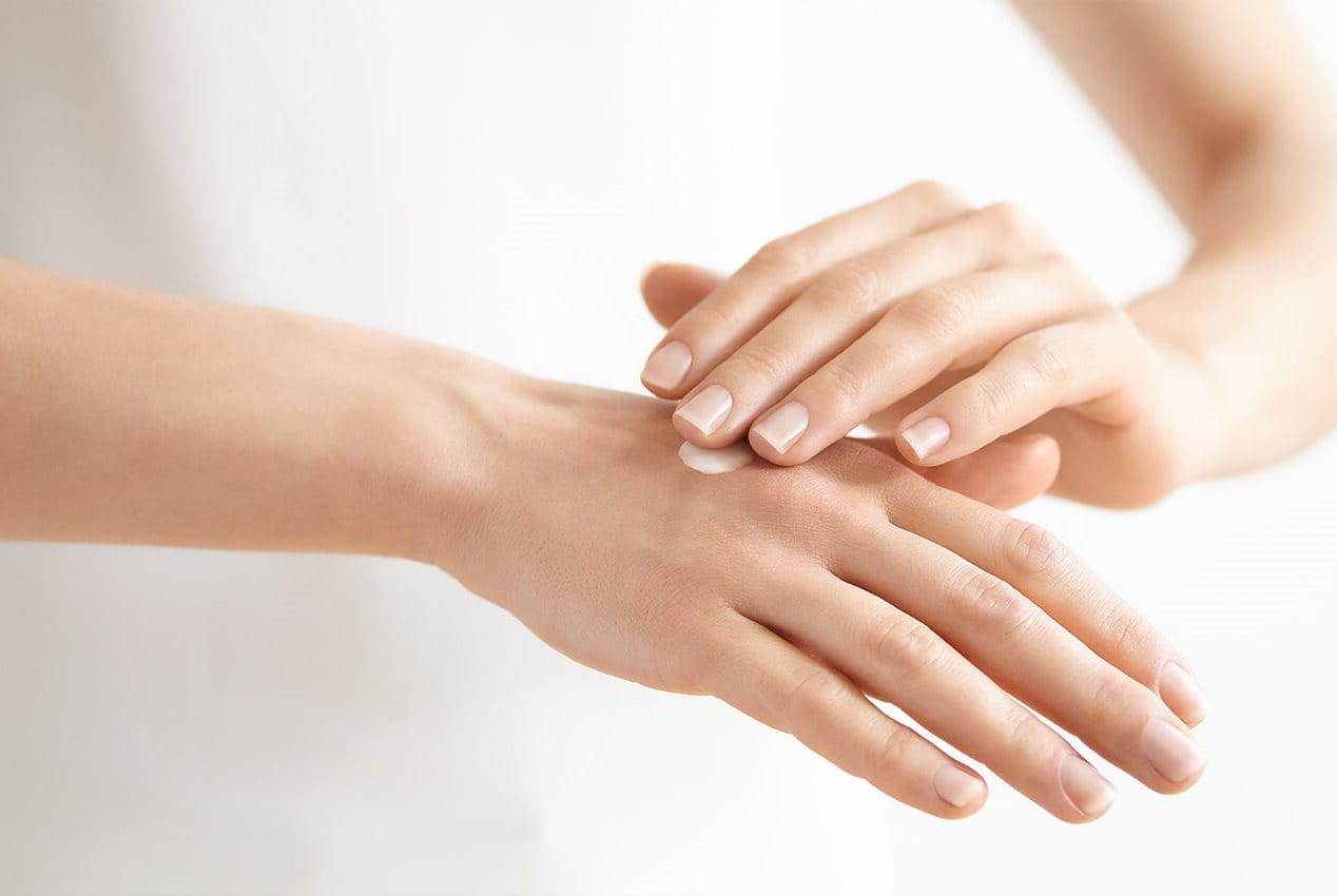 Frau cremet Hand ein