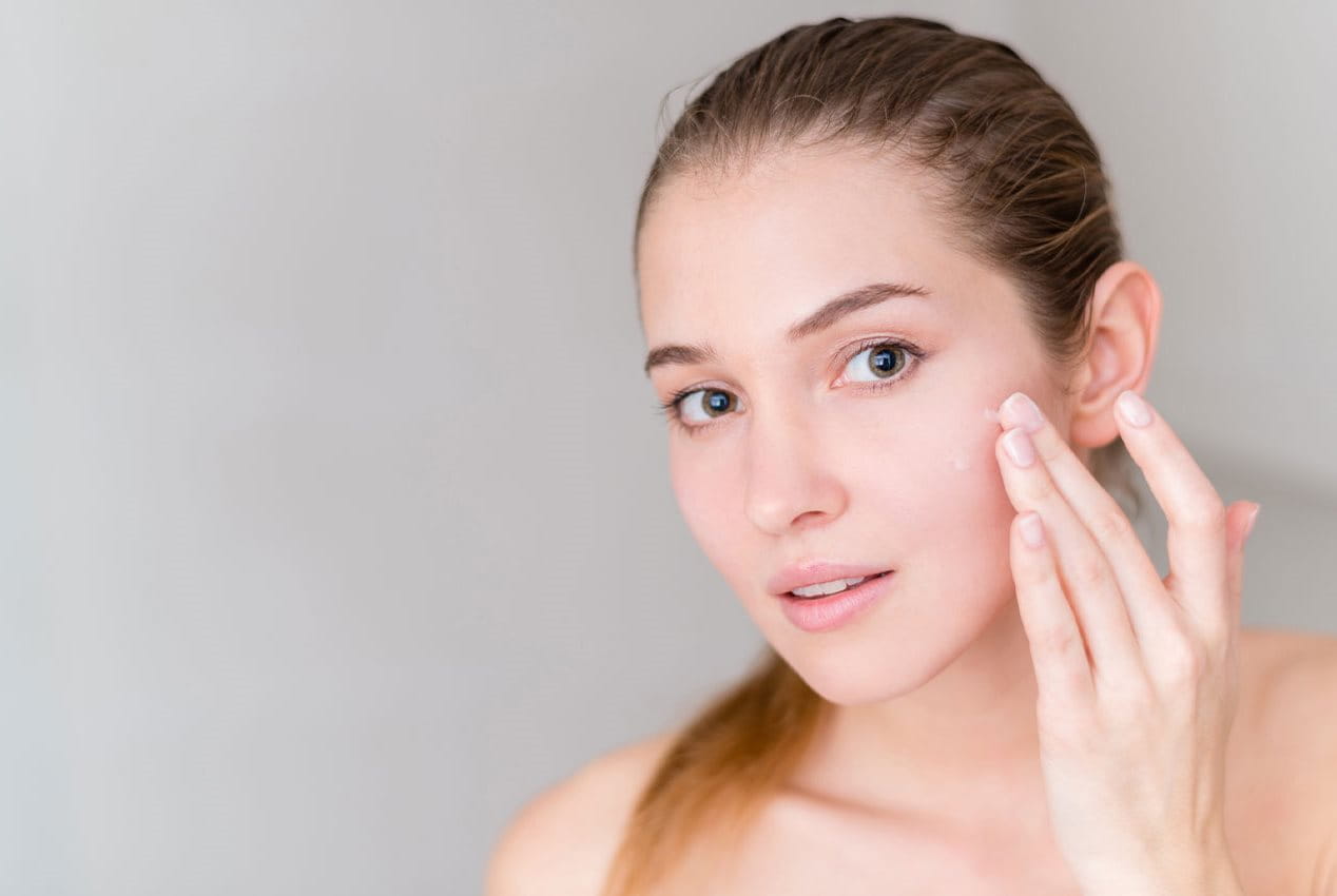 Frau cremt Gesicht ein