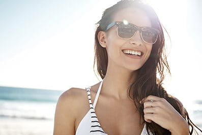 Frau mit Sonnenbrille im Bikini am Strand 