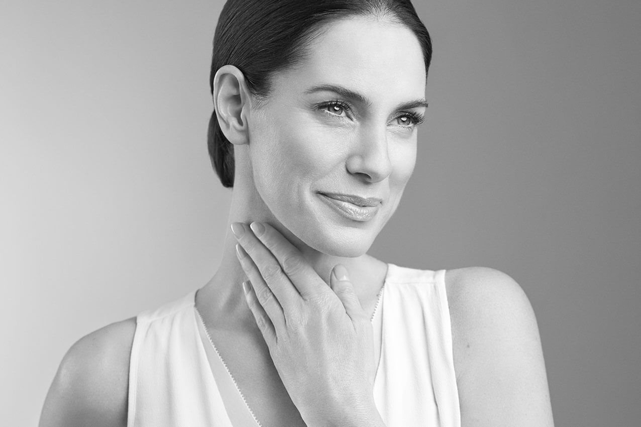 Frau greift sich mit der Hand an den Hals