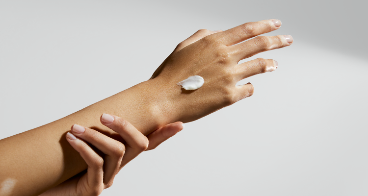 View of an arm and hand being stretched out with a cream product placed on top of the hand.