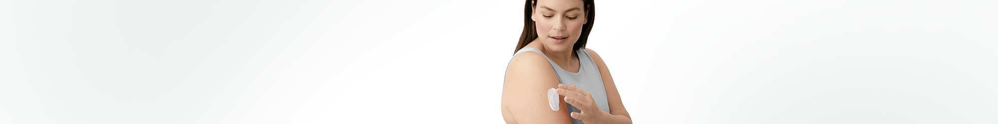 View of a female model with a cream product smudged on her right arm against a white background.