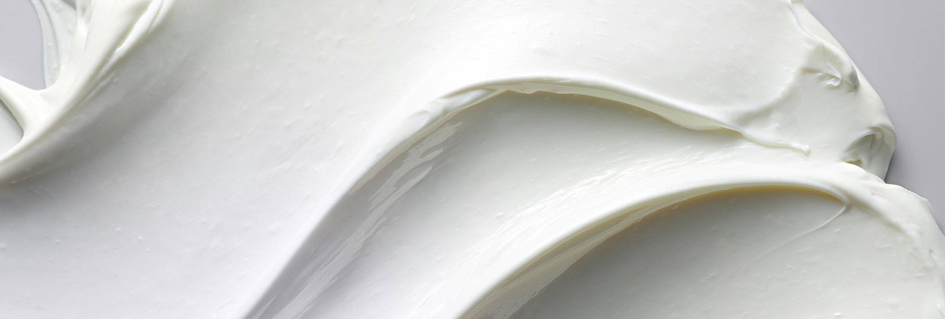 Vue d&rsquo;une crème épaisse Eucerin étalée sur un fond gris.